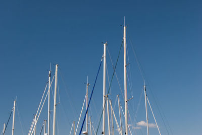 Low angle view of sailboat mast against blue sky