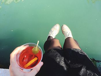 Low section of woman standing by glass against water