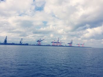 Boats in sea against cloudy sky