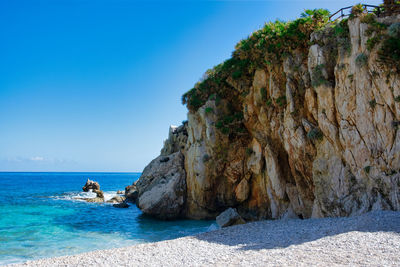 Rock formation on beach against sky