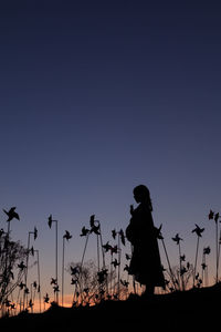 Silhouette people photographing on field against clear sky during sunset