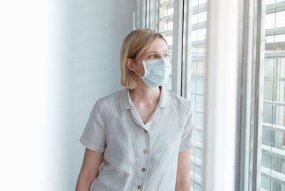 Portrait of a young woman standing against wall