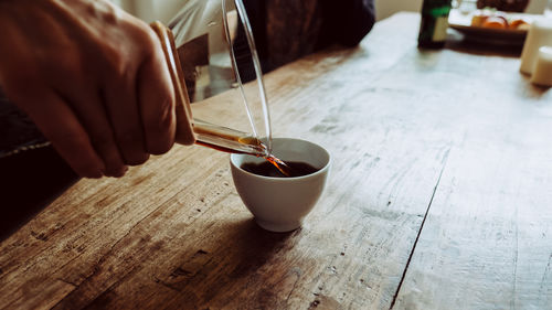 Close-up of hand holding drink on table