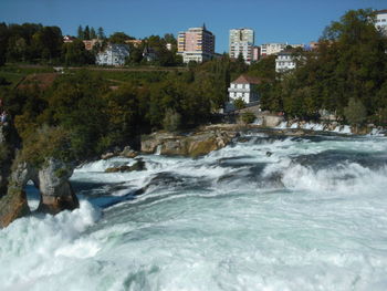 Scenic view of waterfall in city against clear sky