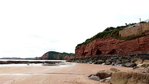 Rock formations on beach against sky