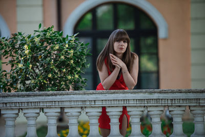 Portrait of woman standing against railing