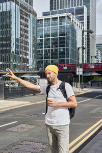 Man with disposable coffee cup hailing ride on sunny day