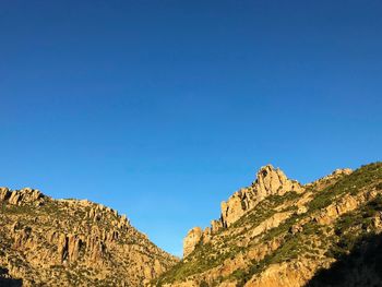 Low angle view of rock formation against clear blue sky