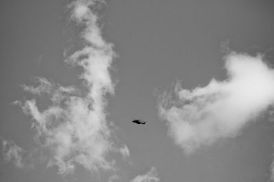 Distant view of silhouette military helicopter flying in sky