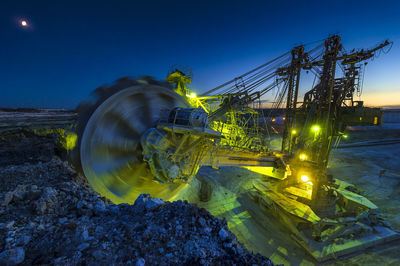 Illuminated ferris wheel against blue sky