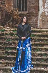 Portrait of a young woman standing against brick wall