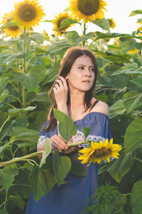 Portrait of young woman standing by flowers