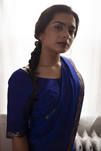 Portrait of young woman standing against wall