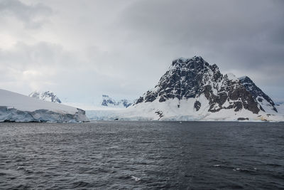 Scenic view of sea and snowcapped mountain against sky