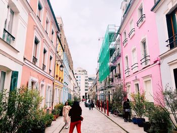 Rear view of women walking on street amidst buildings in city