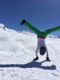 Person skiing on snowcapped mountain against clear blue sky