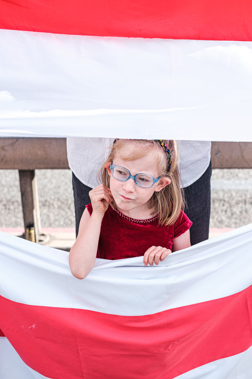 red, one person, women, adult, portrait, glasses, female, front view, lifestyles, day, emotion, leisure activity, clothing, young adult, smiling, outdoors, summer, looking at camera, happiness, water, child, nature, pink, white, childhood, transportation, mode of transportation, relaxation, holiday, headshot, flag