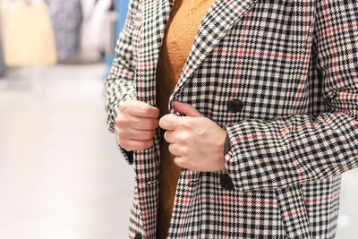 Close-up midsection of woman wearing check patterned overcoat