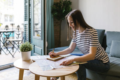 Woman looking away while sitting on table