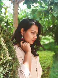 Portrait of young woman standing against plants