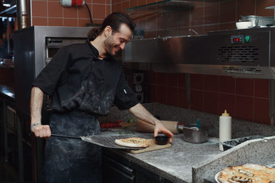 Pizza making process. male chef hands making authentic pizza in the pizzeria kitchen.