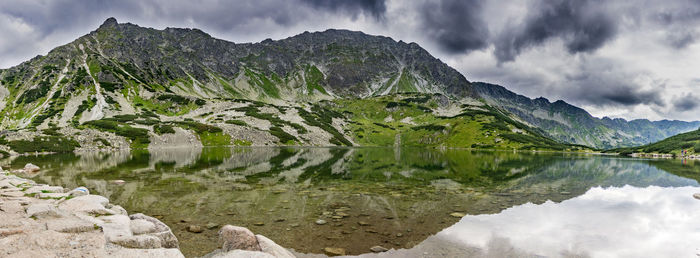 Idyllic view of mountains reflecting on calm lake against cloudy sky