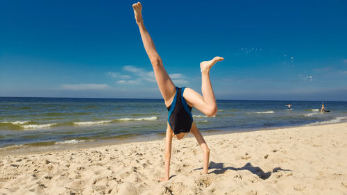 Woman wearing sunglasses on beach against blue sky