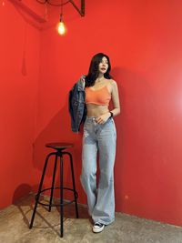 Portrait of young woman standing against yellow wall