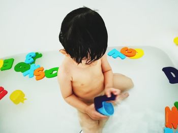 Full length of shirtless boy playing with toy