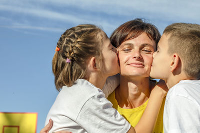 Outdoor hugs, mother and teenage children cuddle gently in the sun on basketball court