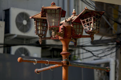 Close-up of rusty metal hanging on pole against built structure