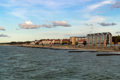 Scenic view of sea by buildings against sky