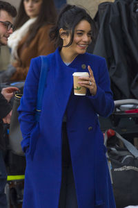 Happy woman holding smart phone while standing on laptop