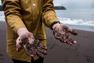 Midsection of person with messy hands standing at beach