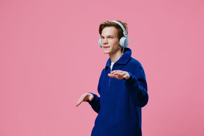 Portrait of young woman standing against yellow background