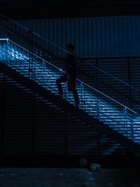 Silhouette man walking on staircase at night