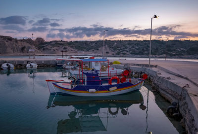 Boats moored in lake against sky during sunset