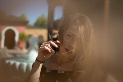 Portrait of woman holding film reel against sky
