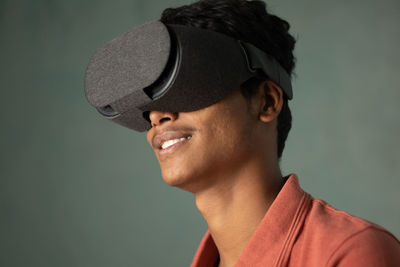 Portrait of young man looking away against gray background