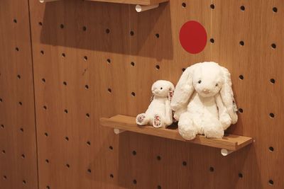Stuffed toy on shelf against wooden wall at home