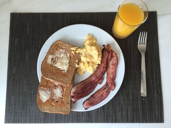 High angle view of breakfast served in plate by orange juice on place mat