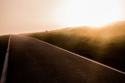 Road amidst landscape against clear sky during sunset