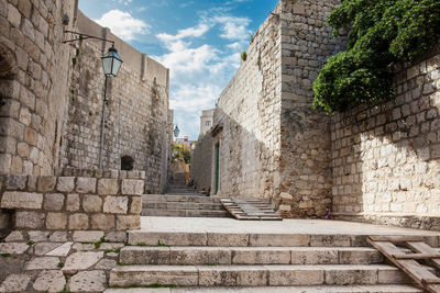 Low angle view of staircase amidst buildings against sky