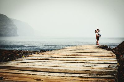 Man standing on sea shore against clear sky