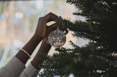Cropped hands of woman decorating christmas tree