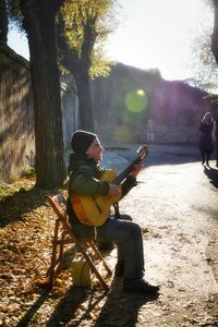 Man playing guitar on tree trunk