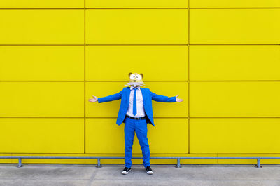 Full length of man standing against yellow wall