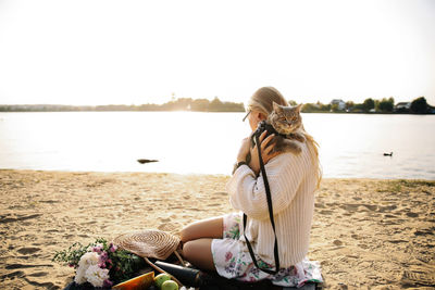 Woman sitting at beach against clear sky