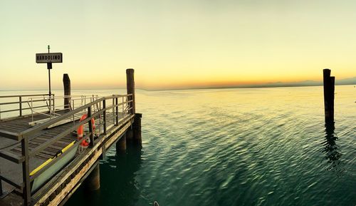 Pier on sea against sky during sunset