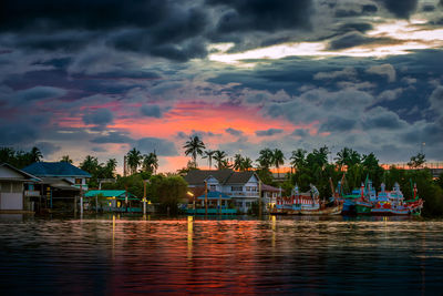 Houses by trees against sky during sunset